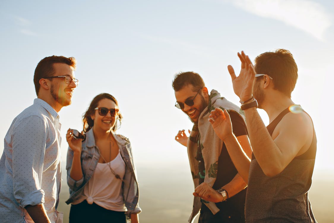 Vier Freunde lachen gemeinsam in der Abendsonne – Freunde werben bei der Fahrschule Bissinger